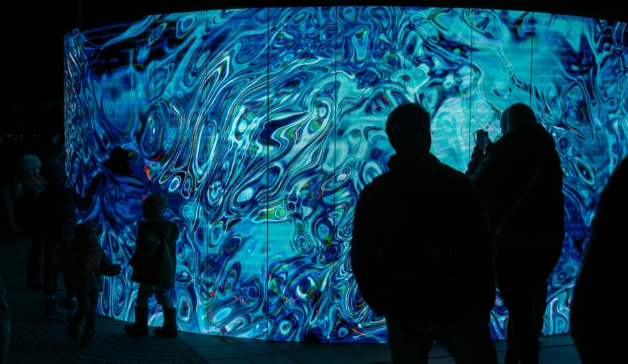 Visitors silhouetted against an immersive light installation